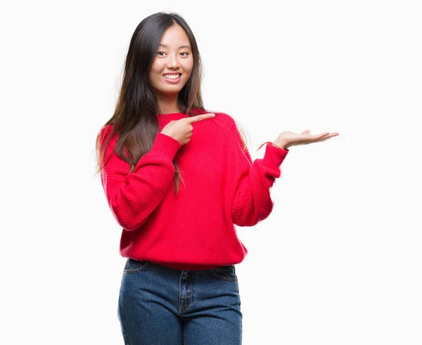 分離背景驚くし 手とを提示 指で指している間カメラに笑顔に冬のセーターを着た若いアジア女性 — ストック写真
