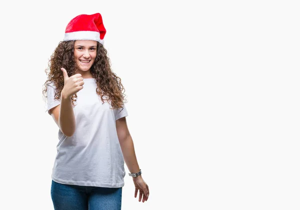 年轻的黑发女孩戴着圣诞帽在孤立的背景做快乐的大拇指与手的手势 通过显示成功来批准镜头的表达 — 图库照片