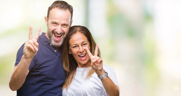 中年西班牙裔休闲夫妇在孤立的背景微笑着与幸福的脸眨眼对着相机做胜利的标志 — 图库照片