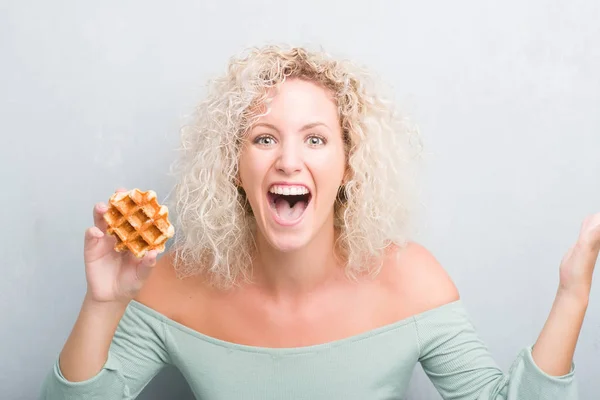 Jovem Loira Sobre Grunge Fundo Cinza Comendo Waffle Belga Muito — Fotografia de Stock