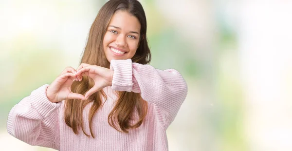 年轻美丽的黑发女人穿着粉红色的冬季毛衣在孤立的背景微笑在爱中显示心脏符号和形状与手 浪漫的概念 — 图库照片