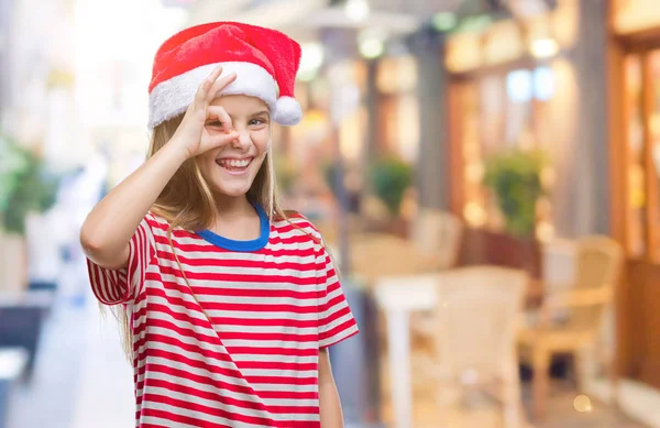 手の笑顔 幸せそうな顔で指を通して見る目で のジェスチャーを行う分離の背景にクリスマス帽子身に着けている美しい少女 — ストック写真