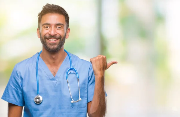 成人西班牙裔医生或外科医生的人在孤立的背景微笑与快乐的脸看着 并指向侧面与拇指向上 — 图库照片