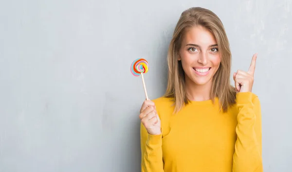 Beautiful Young Woman Grunge Grey Wall Eating Lollipop Candy Surprised — Stock Photo, Image