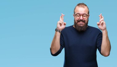 Genç beyaz hipster adam geçiş parmakları umut ve gözleri kapalı ile gülümseyen izole arka plan üzerinde güneş gözlüğü takıyor. Şans ve batıl kavramı.