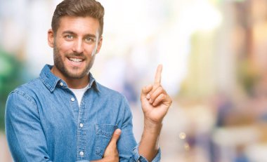 Kameraya bakarak yan el ve parmak ile işaret eden genç yakışıklı adam yüzünde kocaman bir gülümseme ile izole arka plan üzerinde.