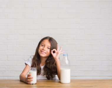 Parmak, mükemmel sembolü ile ok işareti yapıyor süt içme masada oturan genç İspanyol çocuk
