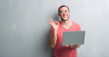 Parmak, mükemmel sembolü ile ok işareti yapıyor bilgisayar dizüstü kullanarak gri grunge duvar üzerinde beyaz delikanlı