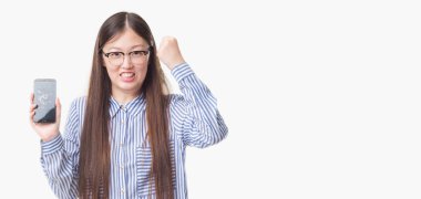 Genç Çinli kadın izole arka plan gösteren rahatsız smartphone ekran kırık ve boşa çıkarmak ile öfke, çılgın ve yükseltilmiş eliyle diye bağıran öfke kavramı bağırarak.