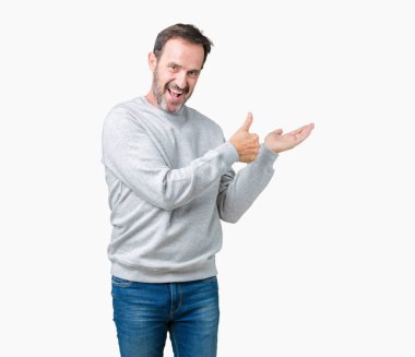 Yakışıklı orta yaş üzerinde bir kazak giyen adam arka plan gösteren palm el izole ve ok hareketini yapıyor, mutlu ve neşeli gülümseyen Yaşasın üst düzey