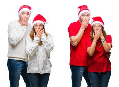 Kolaj bir orta yaş olgun güzel çift beyaz izole arka plan ağız hata için elleriyle kapsayan şok üzerinde Noel şapka giyiyor. Gizli kavramı.