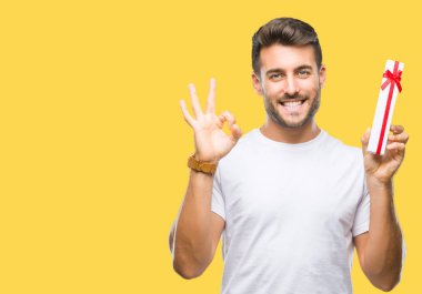 Parmak, mükemmel sembolü ile ok işareti yapıyor izole arka plan üzerinde Sevgililer günü hediyesi veren aşık genç yakışıklı adam