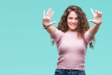 Gösterilen ve parmakları ile işaret izole arka plan üzerinde pembe kazak giyen güzel esmer kıvırcık saçlı Genç kız kendinden emin ve mutlu gülümseyerek süre yedi numara.