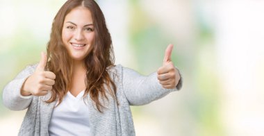 Artı boyutu genç kadın güzel izole arka plan onaylama üzerinde giyen kış ceket el ile pozitif jest yapıyor gülümseyen ve başarı için mutlu yaşasın. Kamera, kazanan jest arıyorsunuz.