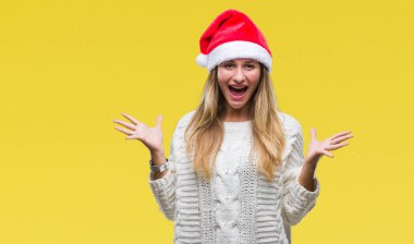Üzerinde Noel şapka giyen genç güzel sarışın kadın deli kutluyor arka plan izole ve başarı için kaldırdı kollarını açarak hayrete ve heyecanlı çığlık gözleri açık. Kazanan kavramı