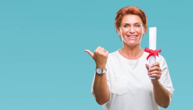 İşaret ve başparmak kadar mutlu yüz gülümseyen tarafı ile gösteren izole arka plan üzerinde derece sertifika tutan kıdemli beyaz kadın