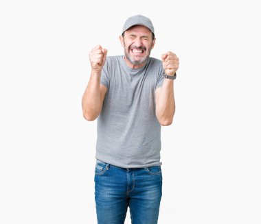 Zafer kutluyor gülümseyen yakışıklı orta yaş ağarmış komuta sizde Spor şapkası izole arka plan üzerinde heyecanlı silah ile başarı için kaldırdı. Kazanan kavramı.