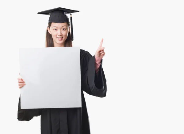 Young Chinese Woman Wearing Graduate Uniform Holding Banner Surprised Idea — Stock Photo, Image