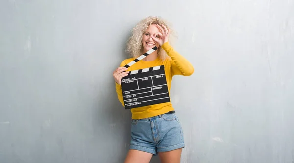 Mladá Blond Žena Nad Grunge Šedá Zeď Drží Calpboard Film — Stock fotografie