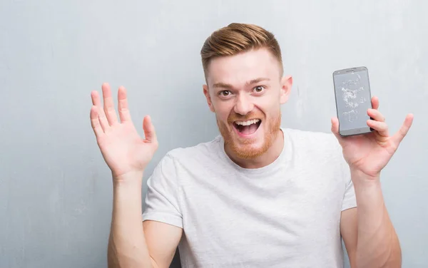 Jeune Homme Rousse Sur Mur Gris Grunge Tenant Smartphone Cassé — Photo