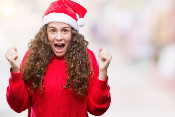 年轻的黑发女孩戴着圣诞帽在孤立的背景庆祝惊讶和惊讶的成功与手臂抬起和睁大眼睛 优胜者概念 — 图库照片