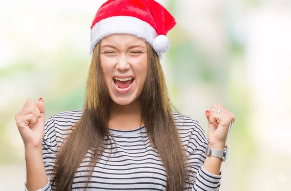 若い美しい白人女性にクリスマスの帽子をかぶっては狂気の背景を分離し 怒って叫んで 叫んで積極的な表現と腕を上げます 欲求不満のコンセプト — ストック写真