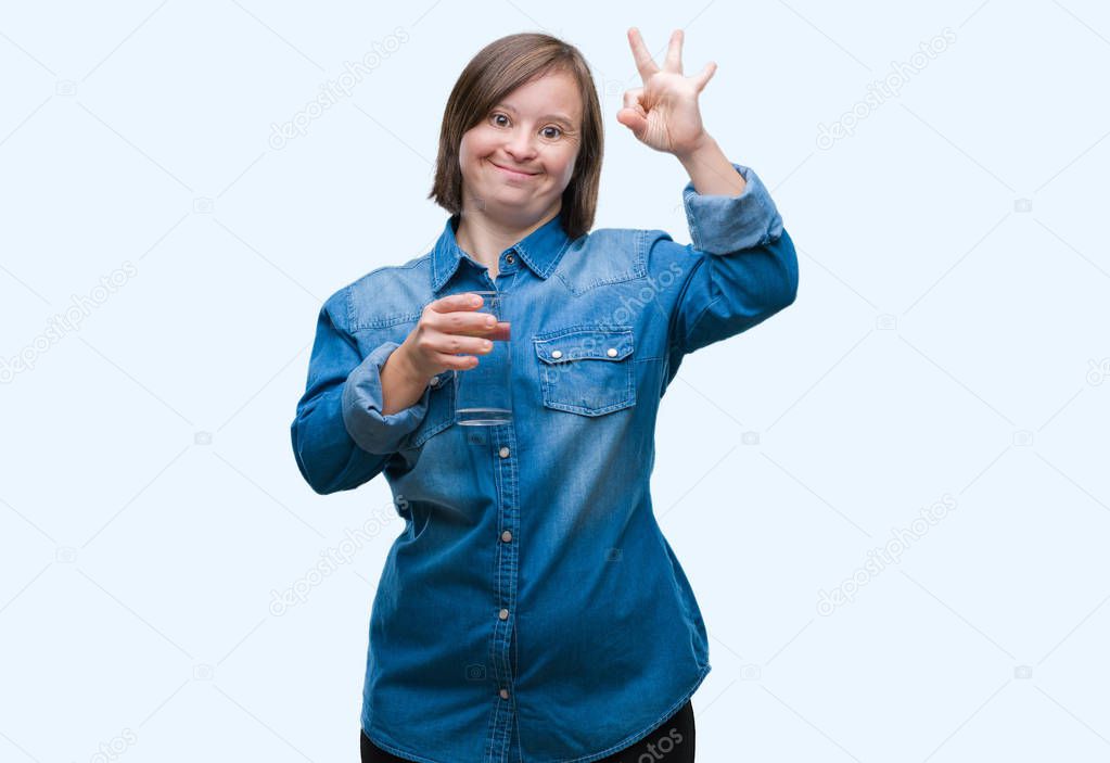 Young adult woman with down syndrome drinking water over isolated background doing ok sign with fingers, excellent symbol