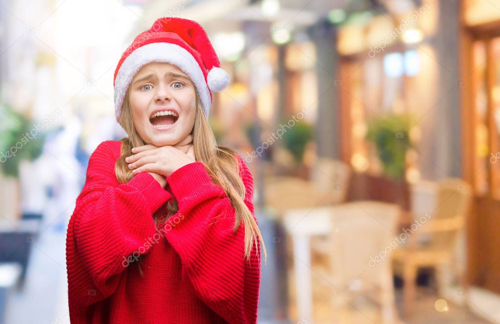 Young beautiful girl wearing christmas hat over isolated background shouting and suffocate because painful strangle. Health problem. Asphyxiate and suicide concept.