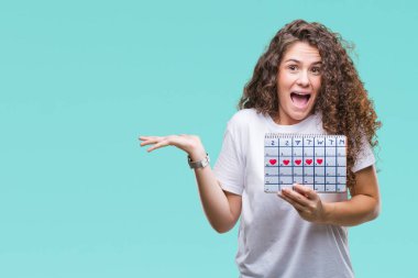 Genç esmer kız adet takvim holding büyük gülümseme ile çığlık zaferini kutluyor arka plan çok mutlu ve heyecanlı, kazanan ifade izole ve ellerini kaldırdı