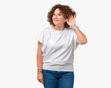 Bir işitme söylenti ya da dedikodu için dinleme kulak üzerinde el ile gülümseyen izole arka plan üzerinde beyaz t-shirt giyen güzel orta ager kadın kıdemli. Sağırlık kavramı.