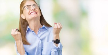 Gülümseyen ve başarı için çığlık izole arka plan çok mutlu ve heyecanlı kaldırdı, silah ile kazanan jest yapıyor üzerinde gözlük güzel orta yaş olgun bir iş kadını. Kutlama kavramı.