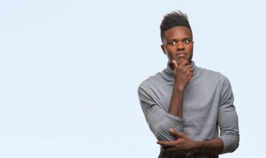 Afrikalı-Amerikalı genç emin çapraz kollar ve çeneme kaldırdı el ile gülümseme ile kameraya bakarak izole arka plan üzerinde. Pozitif düşünce.