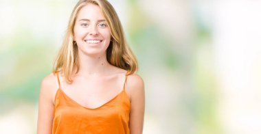 Yüzünde mutlu ve güzel bir gülümseme ile izole arka plan üzerinde turuncu gömlek giymiş güzel ve genç birbayan. Şanslı kişi.