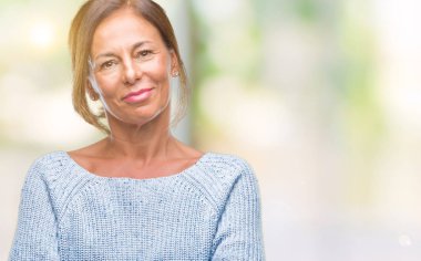 Üzerinde kış kazak giyen orta yaş üst düzey İspanyol kadın mutlu yüz ile gülümseyerek kameraya seyir silah geçti arka plan izole. Olumlu bir kişi.