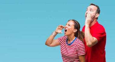 Orta yaş İspanyol çift bağırarak ve ağzı üzerinde el ile yan için çığlık izole arka plan üzerinde aşık. İletişim kavramı.