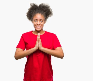 İzole arka plan birlikte emin gülümseyen bağışlanmak ellerle dua genç afro Amerikan kadın.