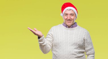 Üst düzey yakışıklı Noel şapka neşeli sunulması ve kameraya bakarak avucunun ile işaret gülümseyen izole arka plan üzerinde.
