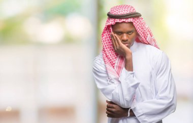 Geleneksel keffiyeh seyir yorgun ve bıkkın ile depresyon sorun Çapraz kollar ile izole arka plan düşünme üzerinde giyen genç Arapça Afrika adam.
