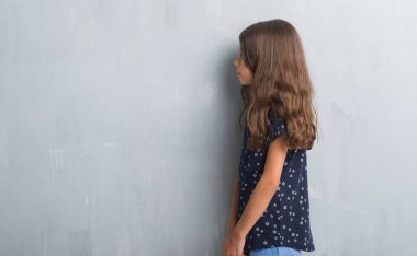 Grunge gri duvar tarafına, arayan genç İspanyol çocuk sakin ol kendine güvenen gülümseme ile doğal yüz pozuyla profili.