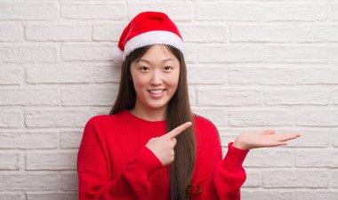 Genç Çinli kadın el ve parmak ile işaret çok mutlu Noel Baba şapkası