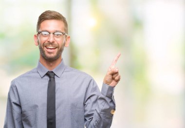 Kameraya bakarak yan el ve parmak ile işaret eden genç yakışıklı iş adamı yüzünde kocaman bir gülümseme ile izole arka plan üzerinde.