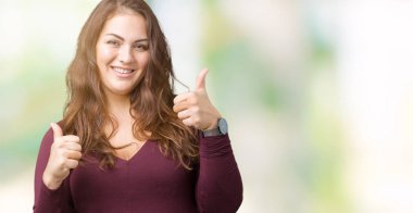 Güzel ve çekici artı boyutu genç kadın el ile pozitif jest yapıyor izole arka plan başarı işareti üzerine bir elbiseyle, gülümseyen ve mutlu yaşasın. Neşeli bir ifadeyle, kazanan jest kameraya bakıyor.