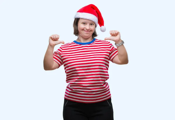 带着唐氏综合症的年轻成年妇女戴着圣诞帽在与世隔绝的背景下 脸上带着微笑 用手指自豪和快乐地指着自己 — 图库照片