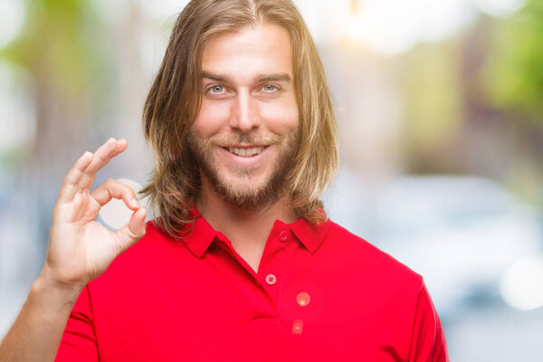 Young handsome man with long hair over isolated background smiling positive doing ok sign with hand and fingers. Successful expression.