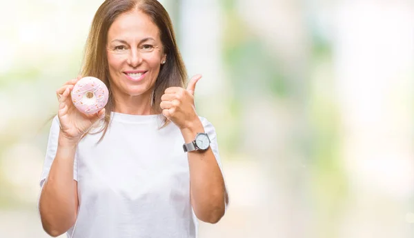笑顔の サイン 優秀な兆候を親指をやって幸せな孤立の背景にピンクのドーナツを食べる中年ヒスパニック系女性 — ストック写真