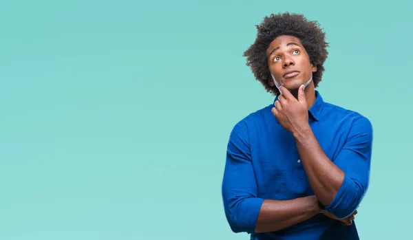 Afro american man over isolated background with hand on chin thinking about question, pensive expression. Smiling with thoughtful face. Doubt concept.