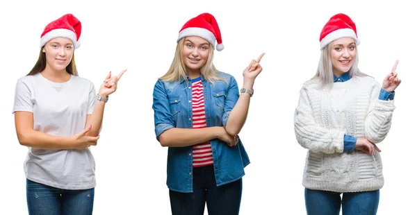一群年轻女性在孤立的背景上戴着圣诞帽 脸上带着灿烂的笑容 用手和手指指着一旁看着镜头 — 图库照片