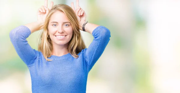 美丽的年轻女子穿着蓝色毛衣在孤立的背景提出有趣和疯狂的手指在头上作为兔子耳朵 微笑着欢快 — 图库照片