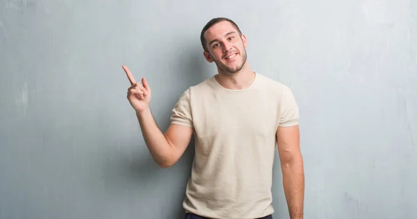 灰色のグランジ壁側の手と指で指す非常に幸せな若い白人男 — ストック写真