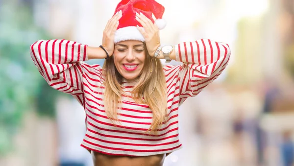 Young beautiful woman wearing christmas hat over isolated background suffering from headache desperate and stressed because pain and migraine. Hands on head.
